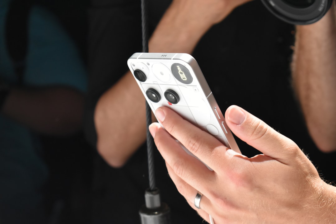 person-holding-a-white-smartphone-with-a-camera-lens-mav5awbafpy